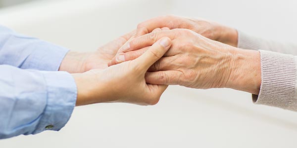 Persona giovane che stringe le mani ad una persona anziama